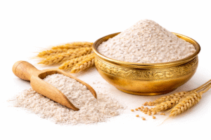 Premium wheat flour (whole wheat atta) in a bowl with wheat grains on white background