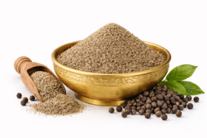 black pepper powder in brass bowl with whole peppercorns and wooden scoop